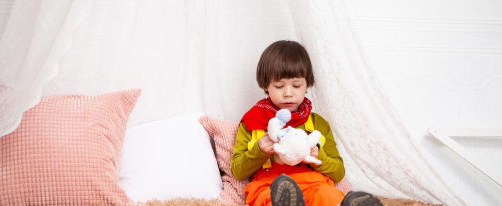 Adorable child sitting indoors with a toy, showcasing innocence and playfulness.
